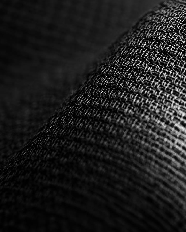Hand stretching a black leggings waistband, soft window light